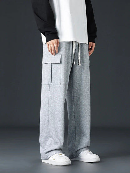 Men's wide-leg gray cargo sweatpants with large side pockets and drawstring waist, styled with white sneakers.