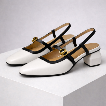 White Italian leather block heel slingback pumps with black straps and gold buckle detail, displayed on white platform