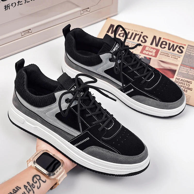 Black and gray patchwork low-top lace-up sneakers with suede panels, knit collar, and white chunky sole displayed on white surface.