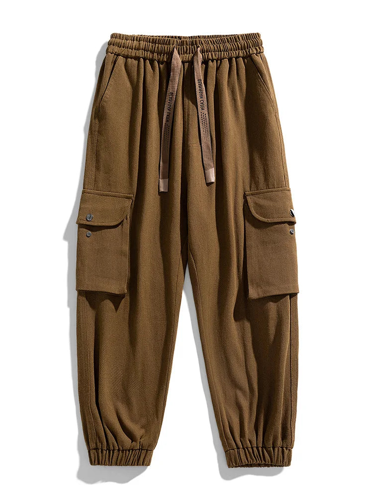Brown cargo jogger pants with elastic waistband, drawstring, side flap pockets, and tapered cuffed ankles for men.