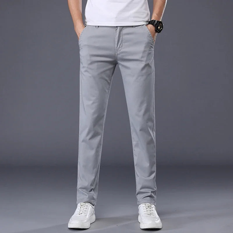 Men's slim fit light gray cotton dress pants paired with white sneakers and a white t-shirt, front view.