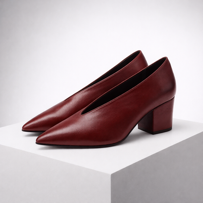 Burgundy leather pointed-toe block heel pumps with V-cut vamp, displayed on white platform against gray background.