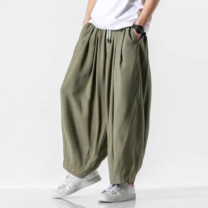 Wide-leg olive green cotton drawstring pants for men with relaxed fit and elastic waistband worn with white sneakers