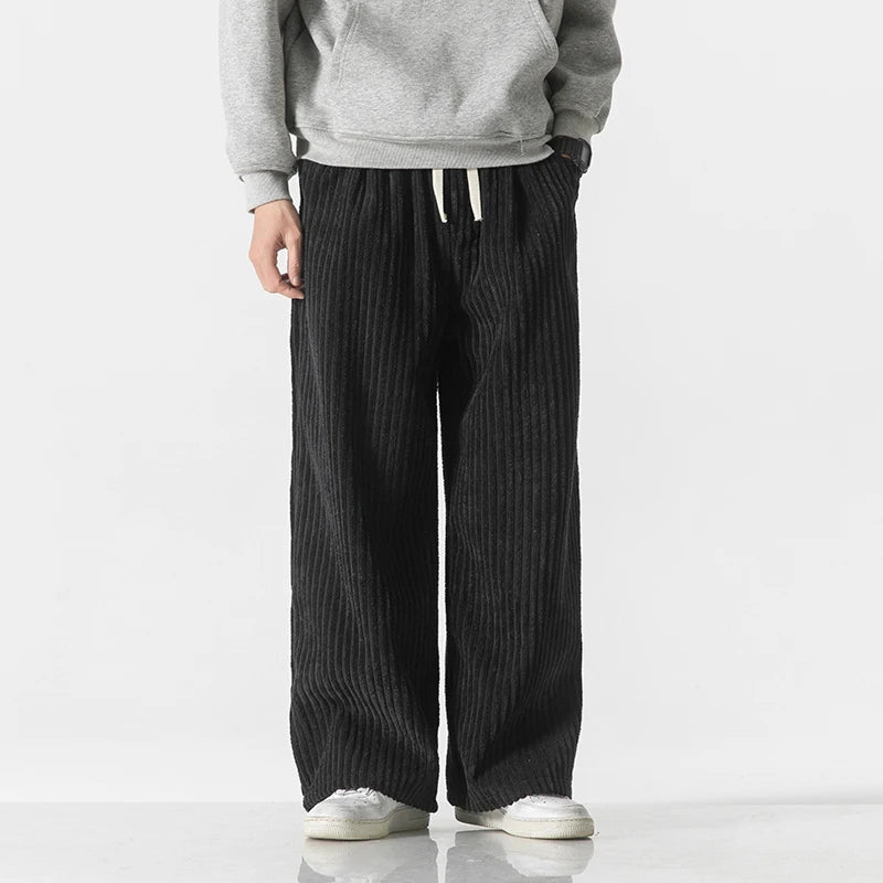 Black wide-leg corduroy drawstring pants worn with gray hoodie and white sneakers, relaxed fit casual style
