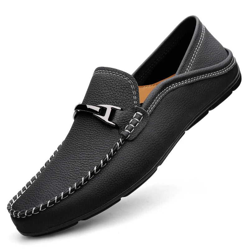 Black men's leather slip-on loafer with silver metal buckle detail and white contrast stitching on white background