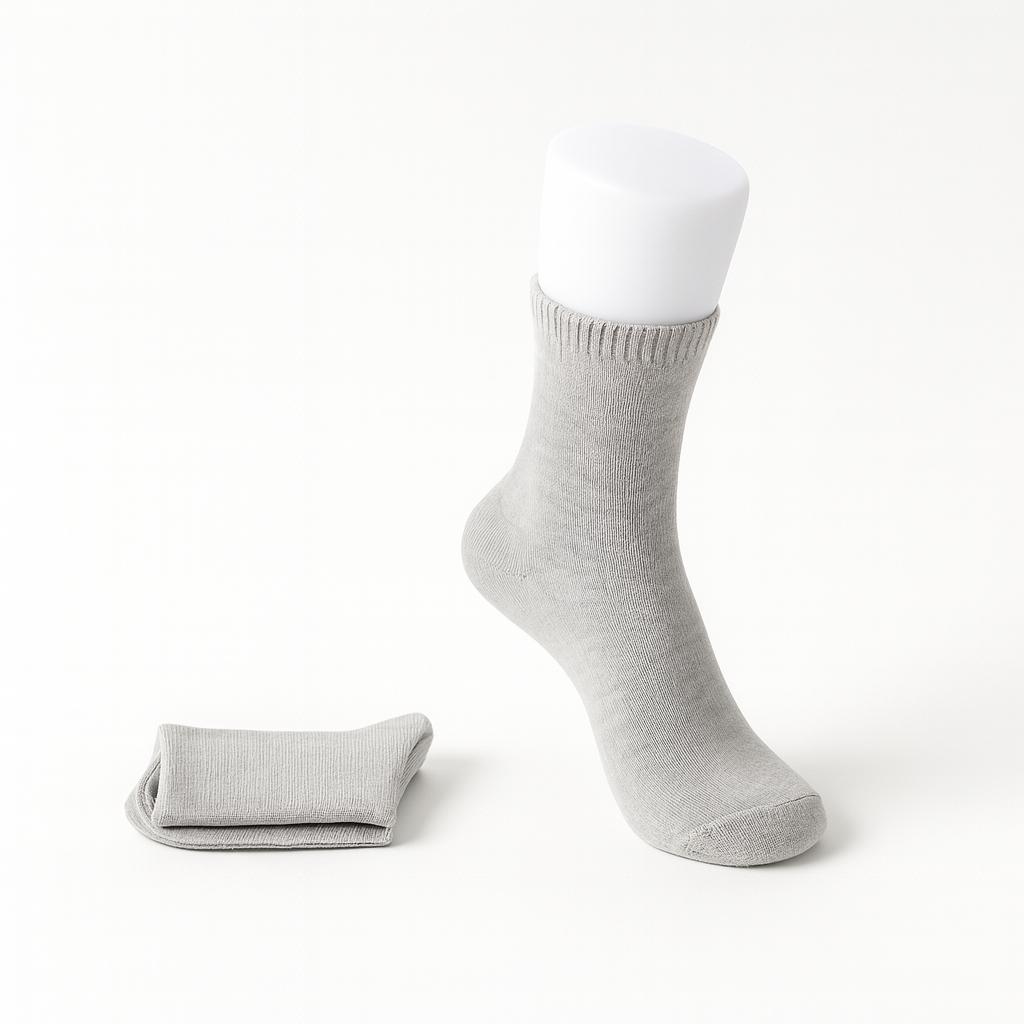 Light gray women's cashmere comfort crew socks displayed on mannequin foot with folded pair beside it.