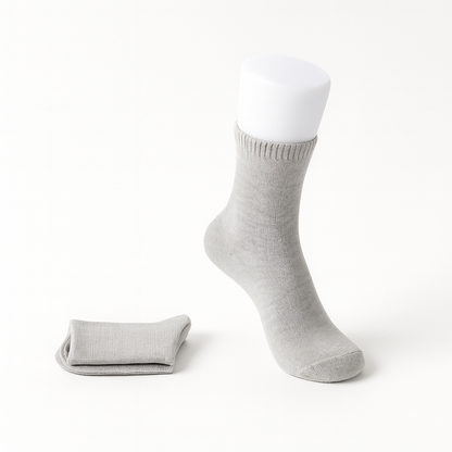 Light gray women's cashmere comfort crew socks displayed on mannequin foot with folded pair beside it.