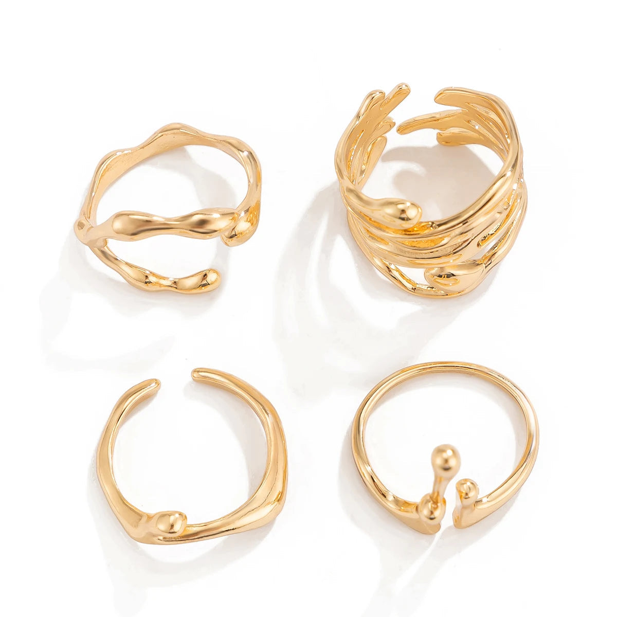 Set of 4 gold adjustable open band rings with wavy, layered, and droplet designs on white background