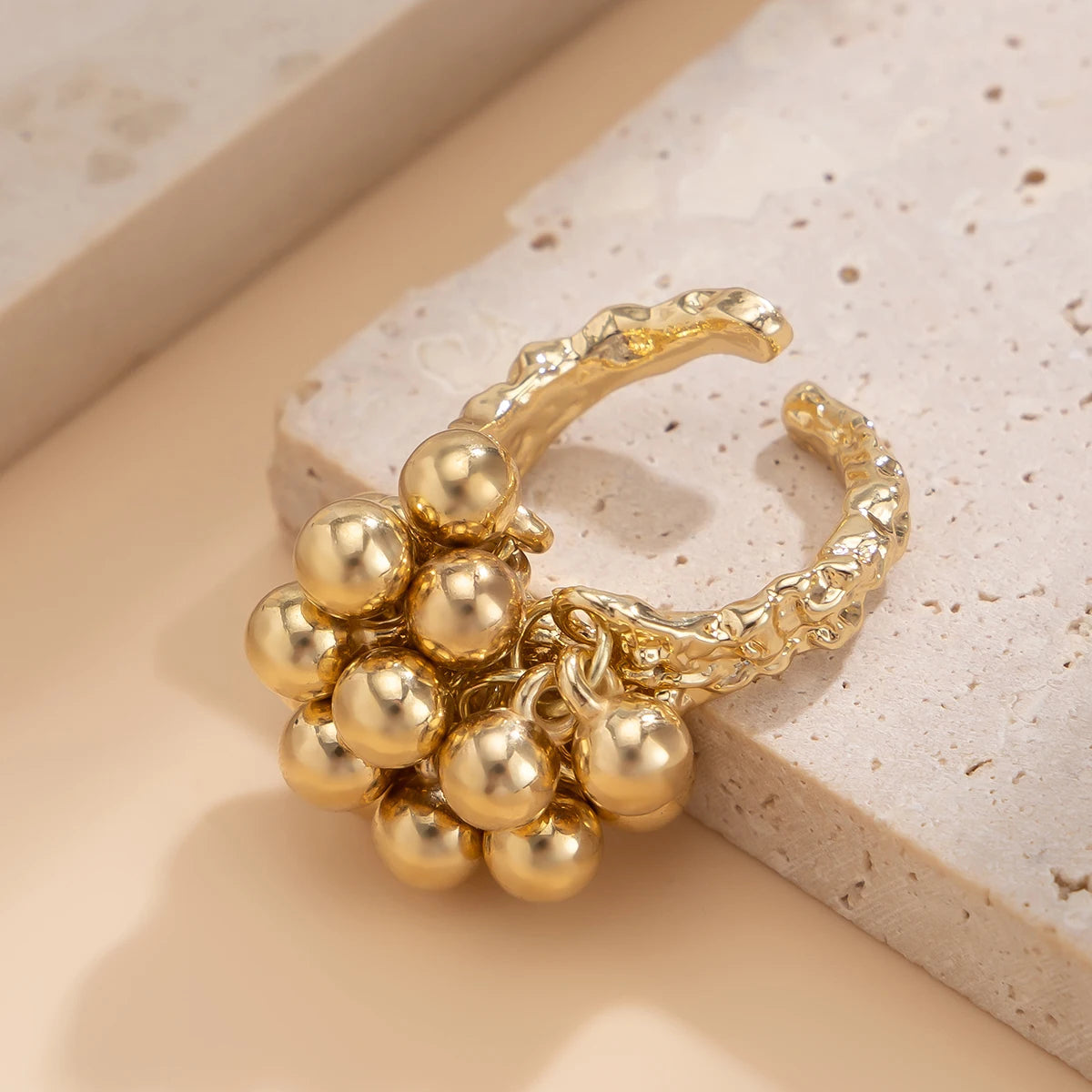 Gold adjustable beaded cluster ring for women on marble stone surface with neutral background