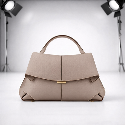 Structured taupe pebbled leather women's handbag with top handle, flap closure, gold hardware, and origami-folded corners.