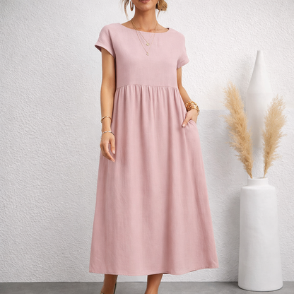 Women's blush pink linen relaxed midi dress with short sleeves, empire waist, side pockets, and A-line silhouette.