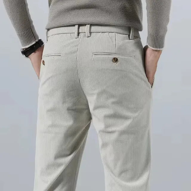 Back view of men's light beige corduroy slim fit chino pants with subtle vertical ribbing and button back pockets.