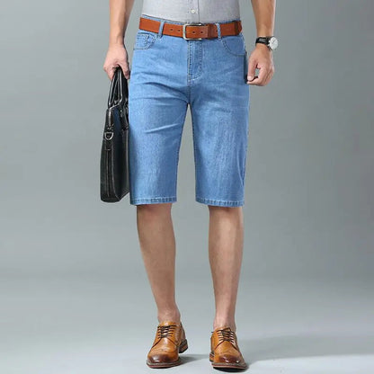 Men's light blue stretch denim shorts with brown leather belt and dress shoes, knee-length casual summer wear
