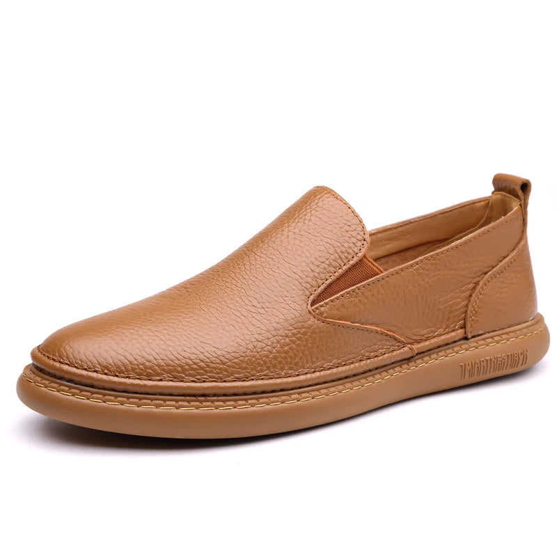 Tan brown men's leather slip-on loafers with textured upper, elastic side panels, and stitched flat sole