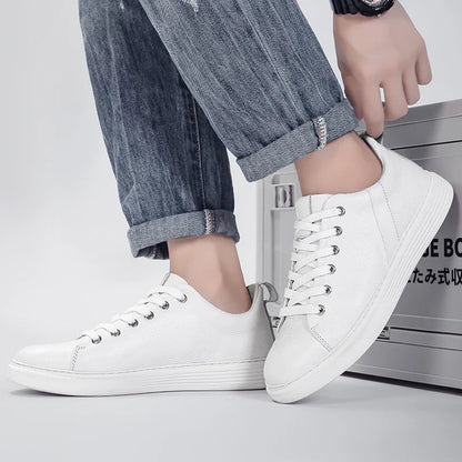Men's white leather low-top sneakers with silver lace eyelets, paired with rolled-up jeans and a black watch.
