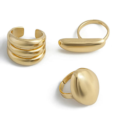 Three gold adjustable rings: multi-band cuff, elongated bar ring, and large dome statement ring on white background.