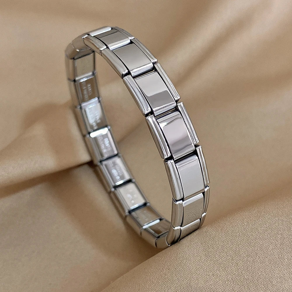 Silver interlocking rectangular link chain bracelet displayed on beige fabric background