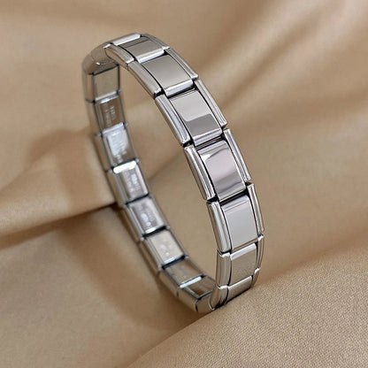 Silver interlocking rectangular link chain bracelet displayed on beige fabric background