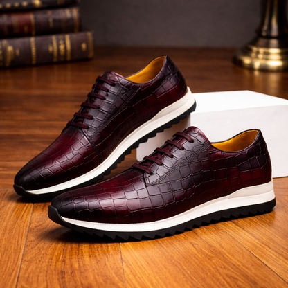 Burgundy croc-embossed leather sneakers for men with white sole and lace-up design on wooden surface