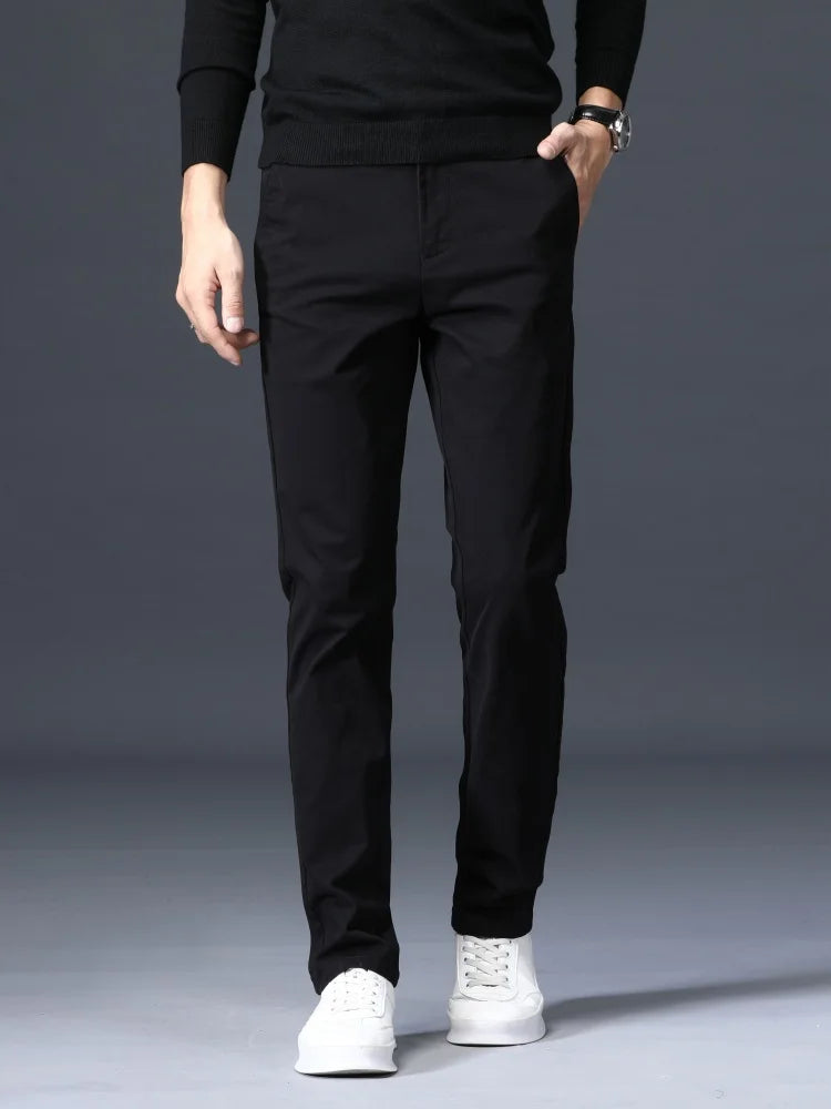 Man wearing slim-fit black cotton dress pants with a black sweater and white sneakers, shown from waist down.