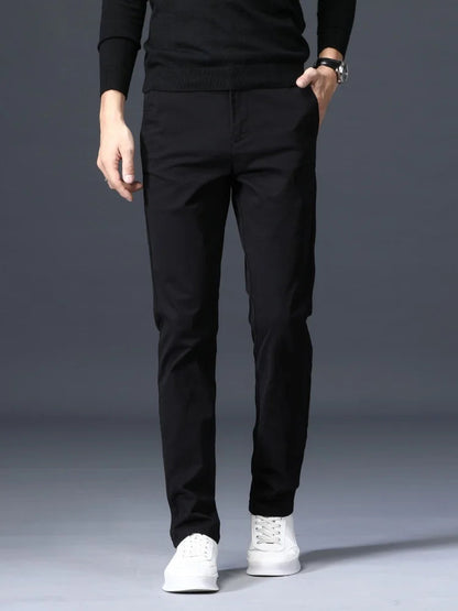 Man wearing slim-fit black cotton dress pants with a black sweater and white sneakers, shown from waist down.