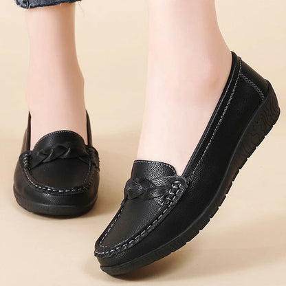Black women's leather slip-on loafers with braided detail and visible stitching on beige background