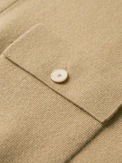 Close-up of a tan merino wool cardigan jacket cuff featuring a cream mother-of-pearl button on a knit flap pocket.