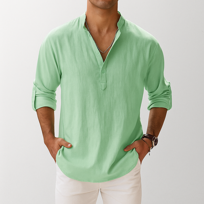 Men's light green linen popover Henley shirt with rolled sleeves, stand collar, and two-button placket, paired with white pants.