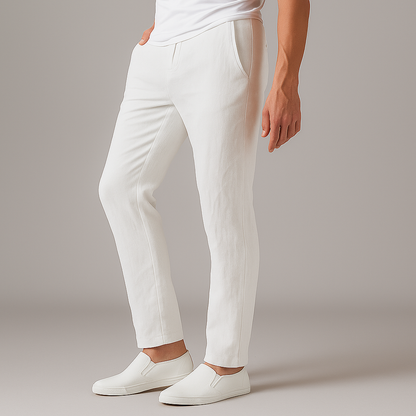 Man wearing slim-fit white linen drawstring pants with side pockets, paired with white slip-on sneakers and a white tee.