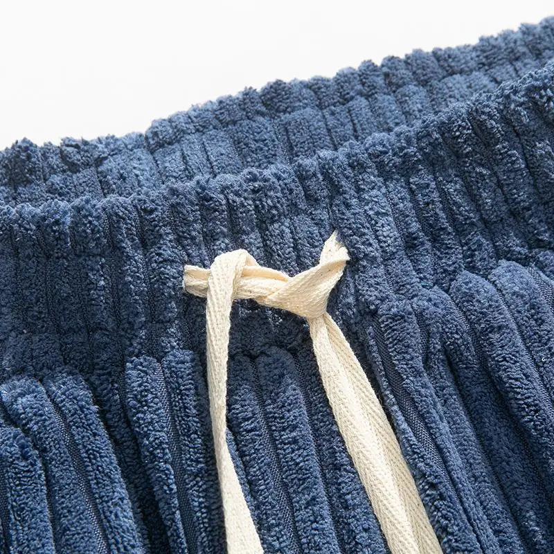Close-up of navy blue wide-leg corduroy pants waistband with cream-colored drawstring tie detail