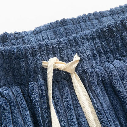Close-up of navy blue wide-leg corduroy pants waistband with cream-colored drawstring tie detail
