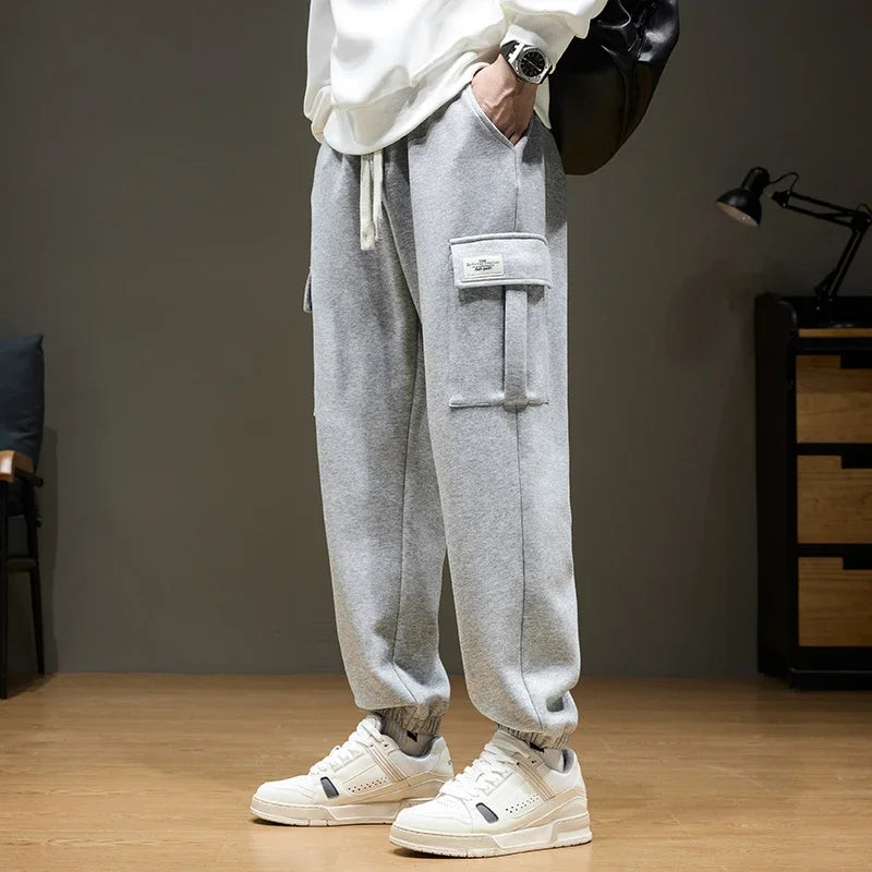 Men's grey cargo joggers with drawstring waist and side pockets paired with white sneakers