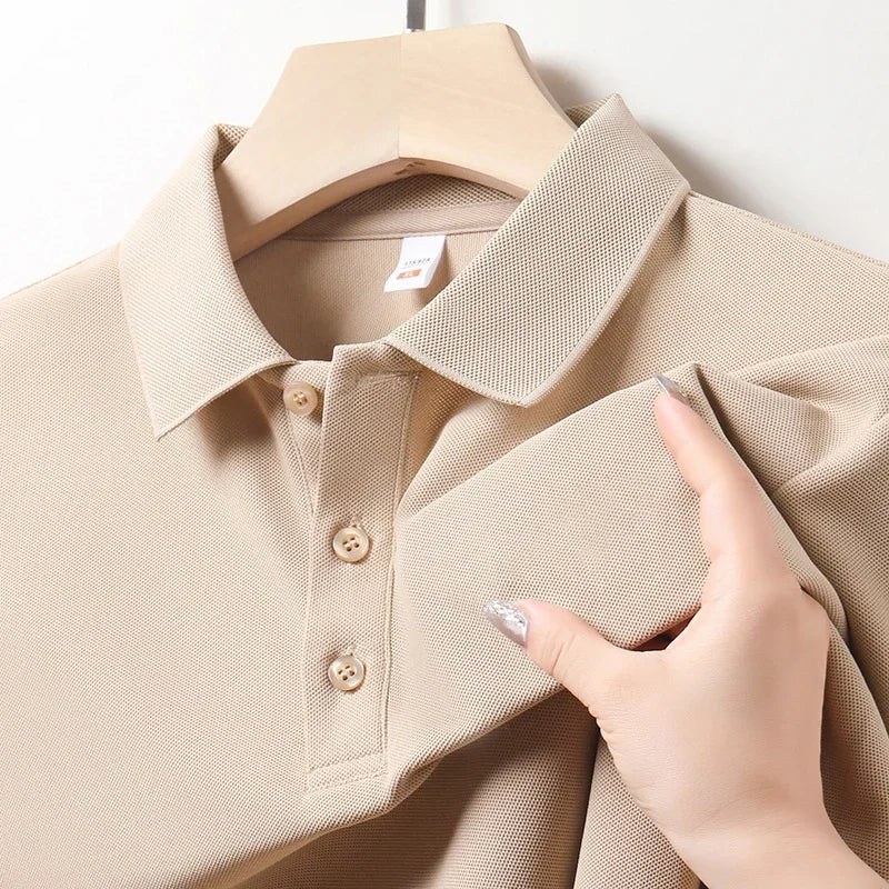 Beige cotton polo shirt with collar and buttons on wooden hanger, hand showing fabric texture
