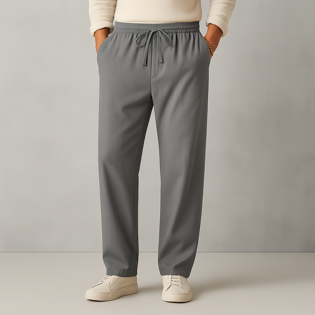 Men's grey linen drawstring casual pants with elastic waistband, straight leg fit, worn with white sneakers and cream sweater.