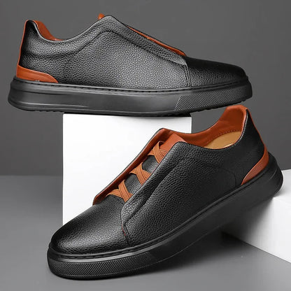 Men's black leather slip-on sneakers with brown contrast trim and thick black sole on white display box