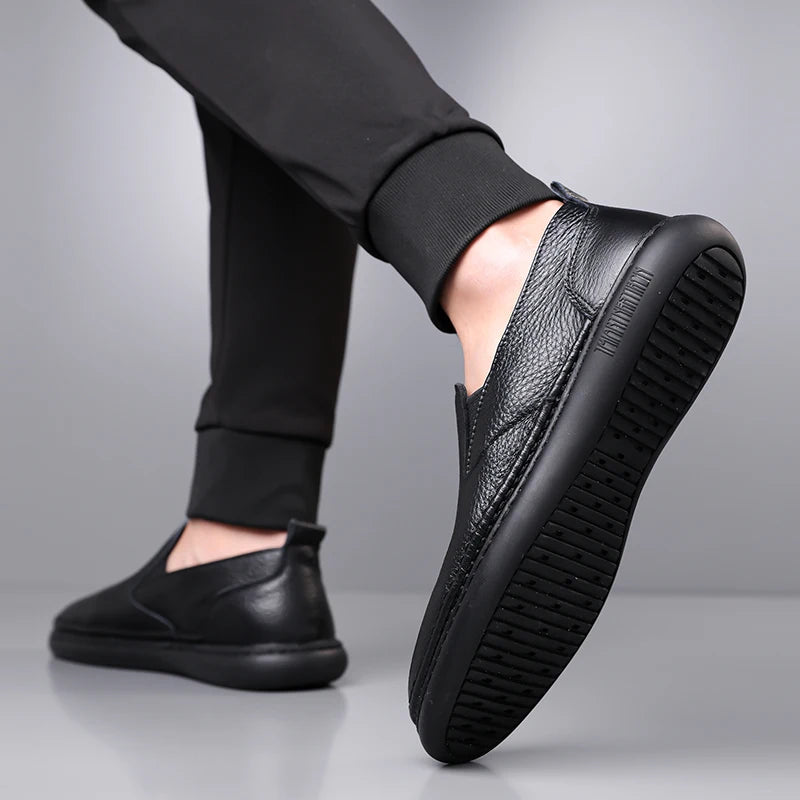 Black leather slip-on loafers with textured upper and rubber sole, shown on male model wearing black pants