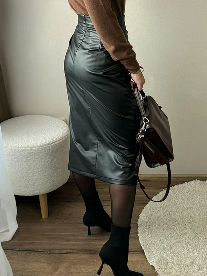 Women's black vegan leather wrap midi skirt styled with brown sweater, black tights, and heeled boots, side view.