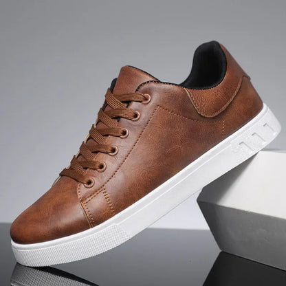 Brown leather lace-up low-top sneakers for men with white sole and padded collar on gray background