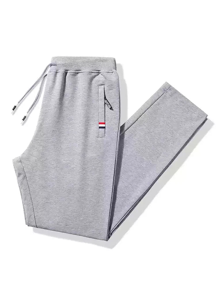 Gray men's cotton drawstring sweatpants with zip pocket accent stripe detail and elastic waistband, folded flat lay view