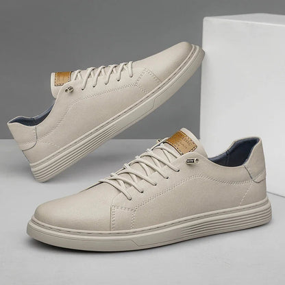 Beige men's leather low-top lace-up sneakers with gold accent tab, flat sole, and blue interior lining shown from two angles.