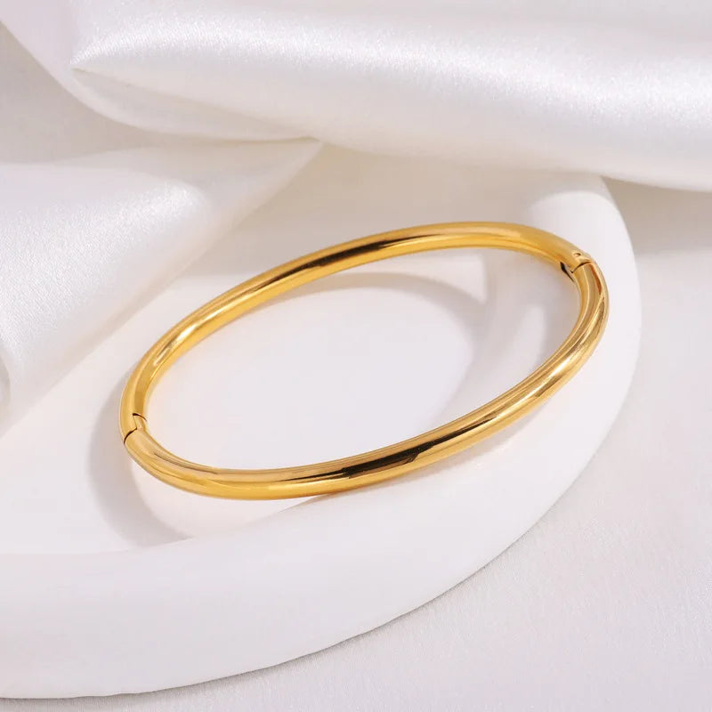 Non-tarnish gold bangle bracelet for women, hinged clasp, polished finish on white display stand