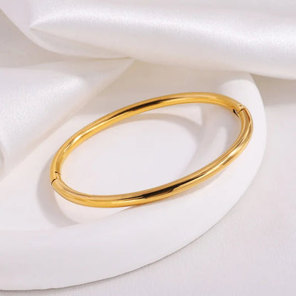 Non-tarnish gold bangle bracelet for women, hinged clasp, polished finish on white display stand