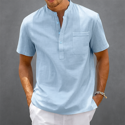 Men's light blue linen short-sleeve Henley shirt with band collar, chest pocket, and three-button placket.