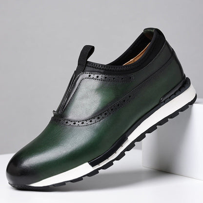 Green leather men's slip-on loafers with brogue perforations, black collar, and white rubber sole on white platform.