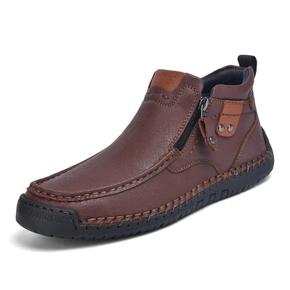 Dark brown leather men's ankle boots with side zipper, hand-stitched detailing, and contrast tan accents on rubber sole