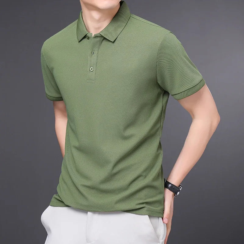 Men's short-sleeve cotton polo shirt in olive green with button collar and slim fit, worn with white pants.