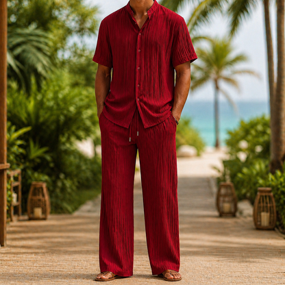 Man wearing red linen short-sleeve button shirt and matching drawstring pants set in tropical beach setting.