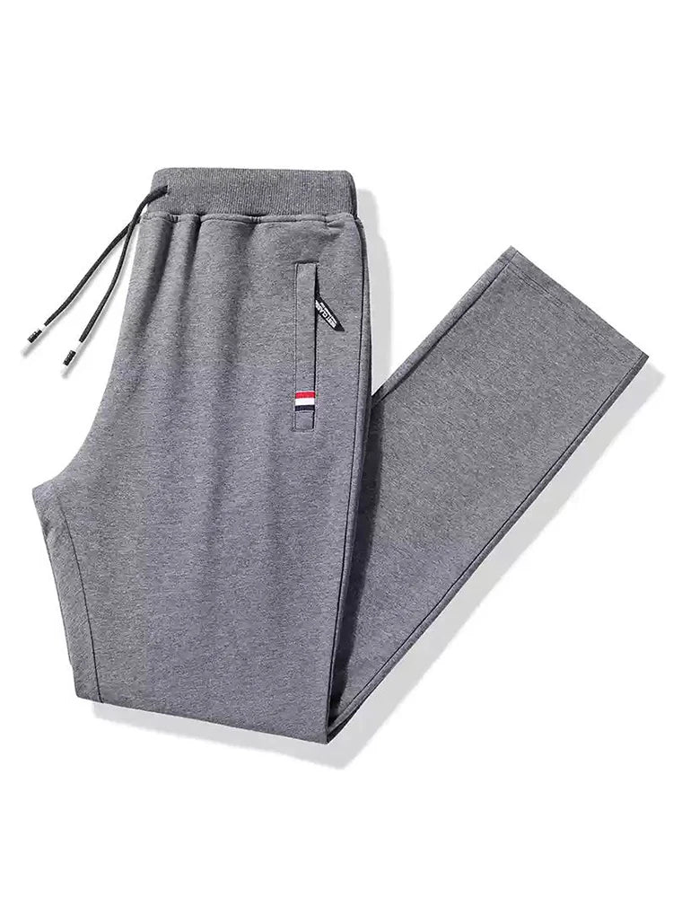 Gray men's cotton drawstring sweatpants with zippered pocket, elastic waistband, and tricolor stripe detail, folded flat.