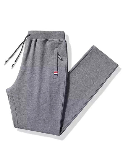 Gray men's cotton drawstring sweatpants with zippered pocket, elastic waistband, and tricolor stripe detail, folded flat.