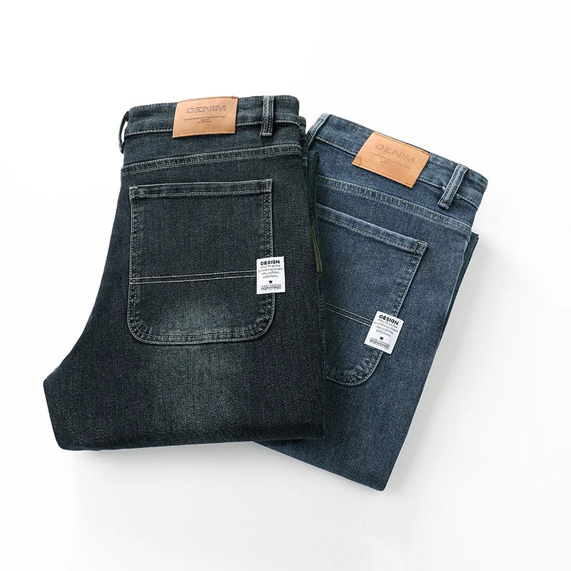 Two folded men's straight leg stretch denim jeans in dark charcoal and medium blue wash with leather patch labels.